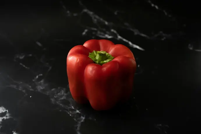 a close up of a pepper on a black surface